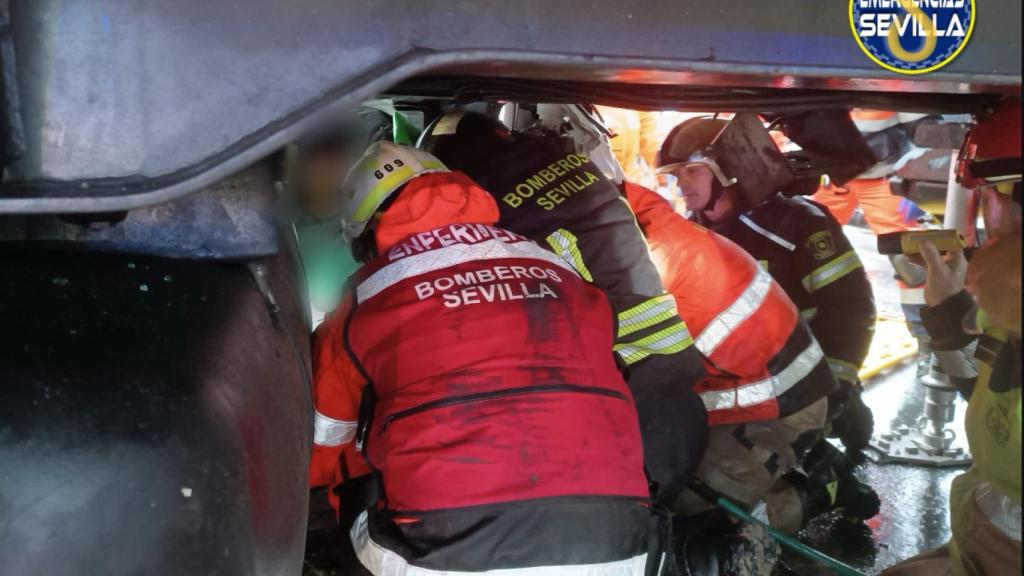 Bomberos y policías tratan de sacar al conductor de su coche.