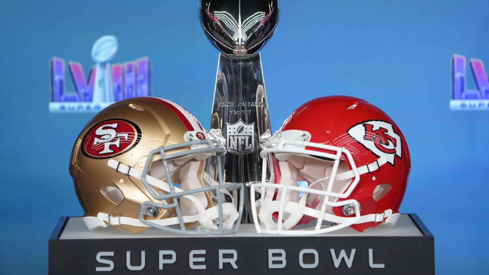 Un caso de los San Francisco 49ers y otro de los Kansas City Chiefs junto al trofeo de la Super Bowl