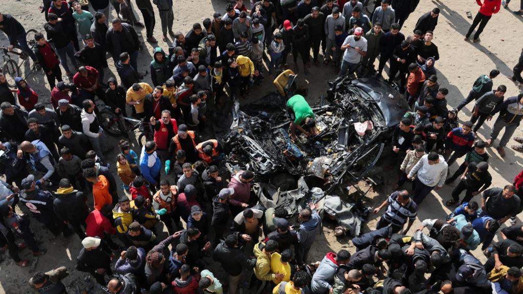 Ciudadanos palestinos inspeccionan un automóvil tras ser alcanzado por un ataque israelí, en Rafah.