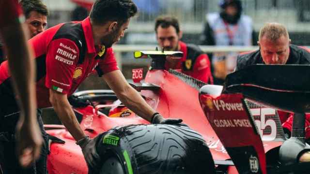 Imagen del Ferrari en los boxes junto a varios mecánicos.