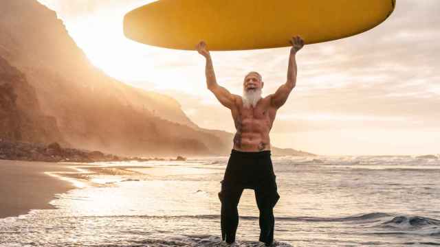 Imagen de archivo de un hombre mayor que se mantiene en forma haciendo surf.