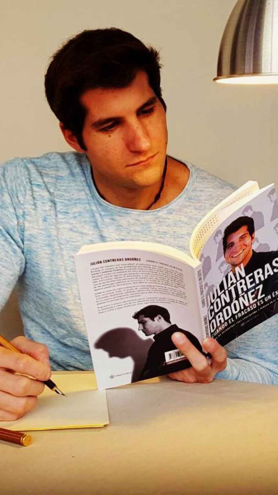 Julián Contreras, posando al tiempo que lee uno de sus libros.