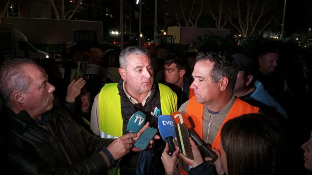Los agricultores Juan Antonio Pérez (a la derecha y con el chaleco naranja) y Javier,  atendiendo a la prensa al salir de la reunión con López Miras.