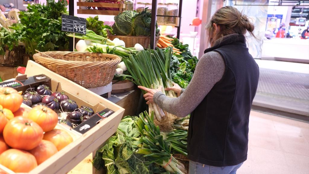 Una mujer coloca los 'calçots’ en su establecimiento de verduras.