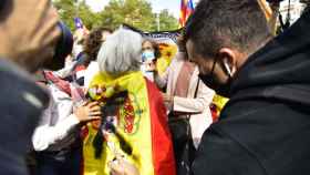 El acusado, Joan B. pinta una cruz en la bandera de España que lleva una mujer en un acto en Barcelona en 2020.