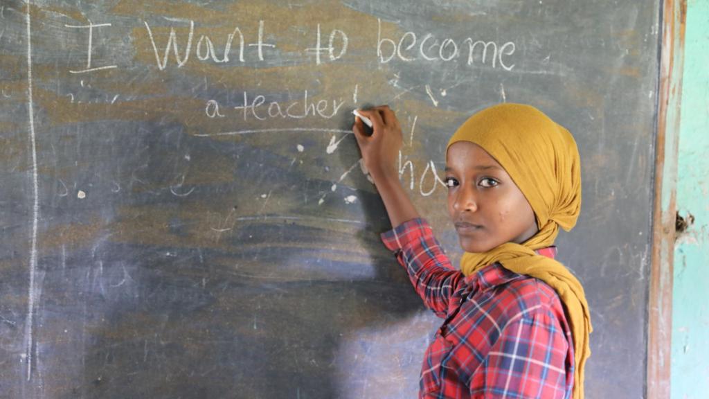 Zemzem escribe en una pizarra I want to be a teacher (Quiero ser profesora, en inglés).