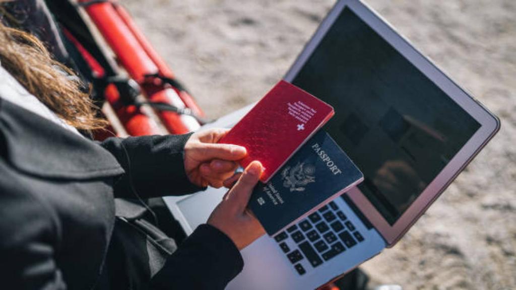 Una chica teletrabajando y con sus pasaportes en la mano