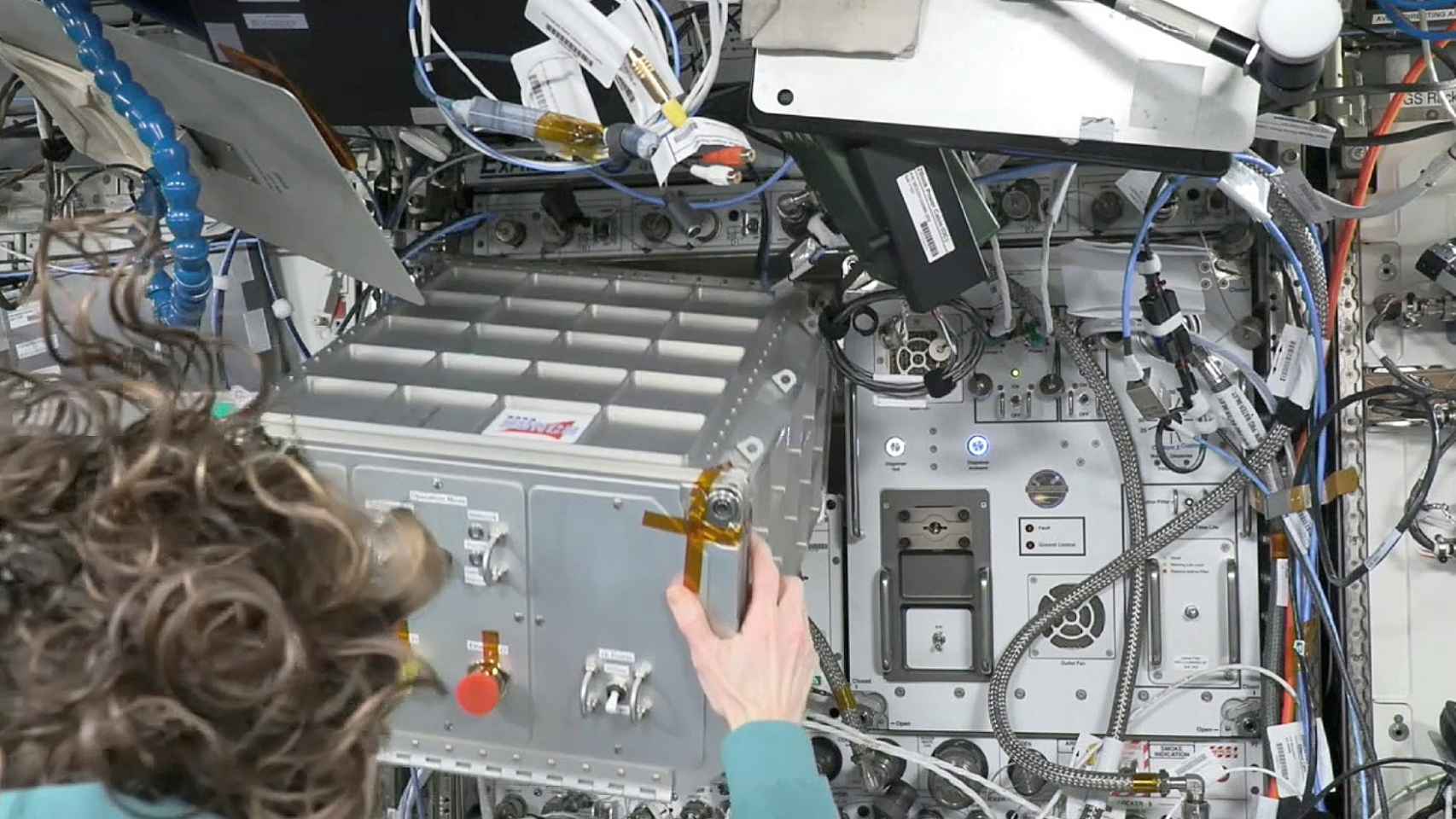 An ISS astronaut takes out the small metal box in which he traveled to spaceMIRA