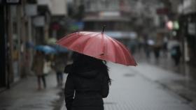 Una persona se resguarda de la lluvia en una imagen de archivo.