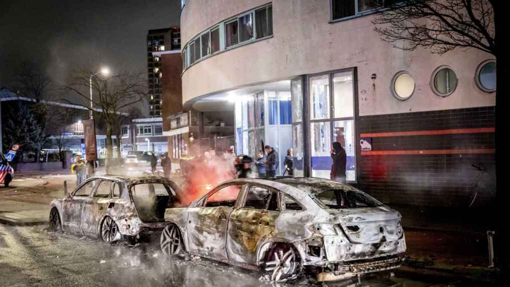 Dos vehículos de policía carbonizados tras los disturbios en La Haya