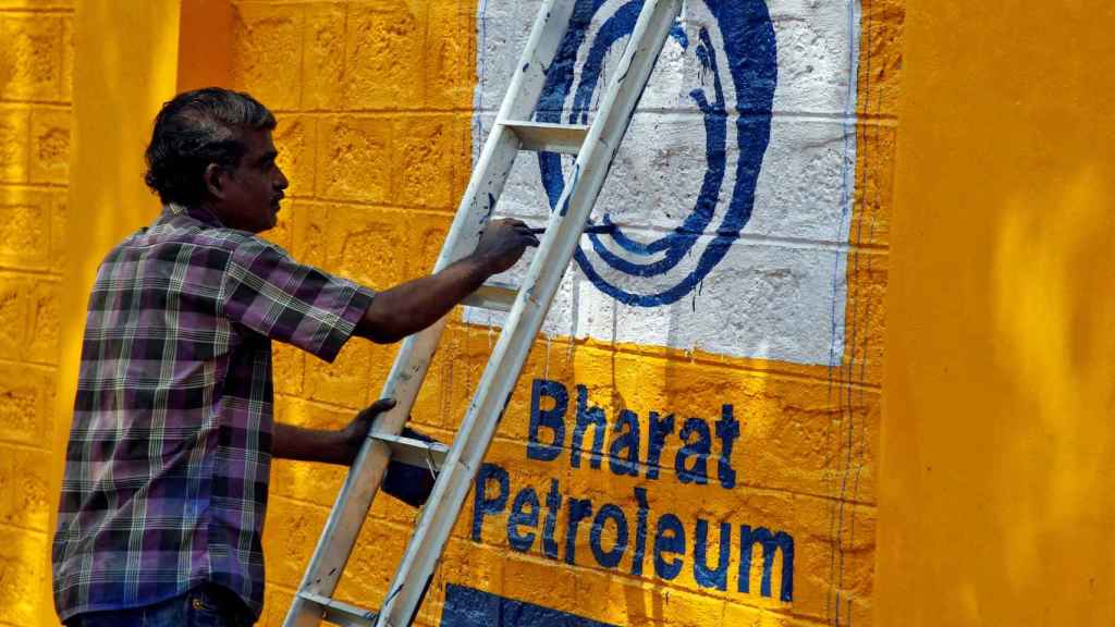 Un hombre pinta el logotipo de Bharat Petroleum Corp en una pared de las afueras de Kochi.