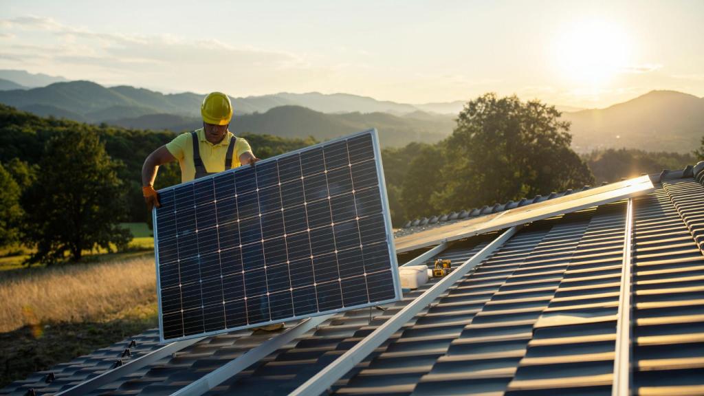 Un operario instalando un panel solar en el tejado de una vivienda