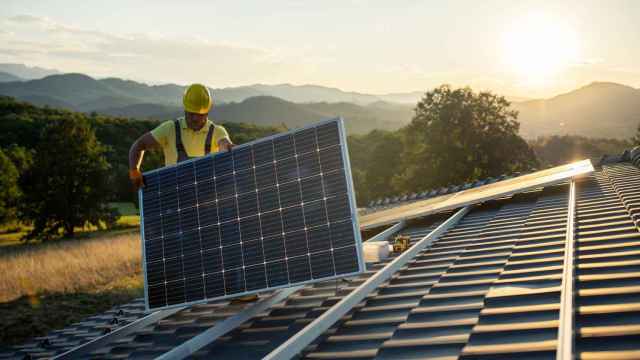 Un operario instalando un panel solar en el tejado de una vivienda