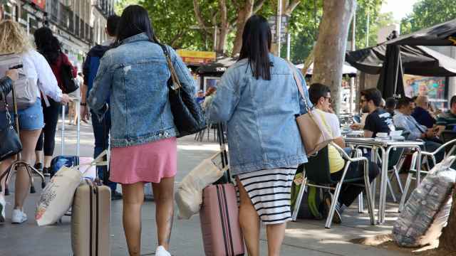 Dos turistas caminan con sus maletas por el centro de Madrid
