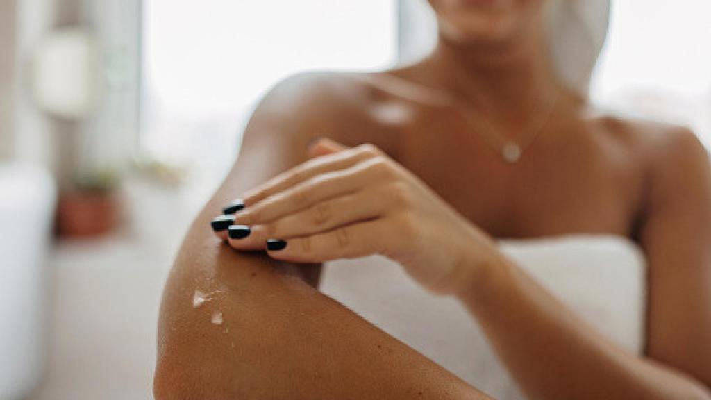 Una mujer aplicando crema hidratante para luchar con la sequedad de sus codos.