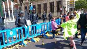Una manifestante arroja un limón contra un agente de la Policía Nacional.