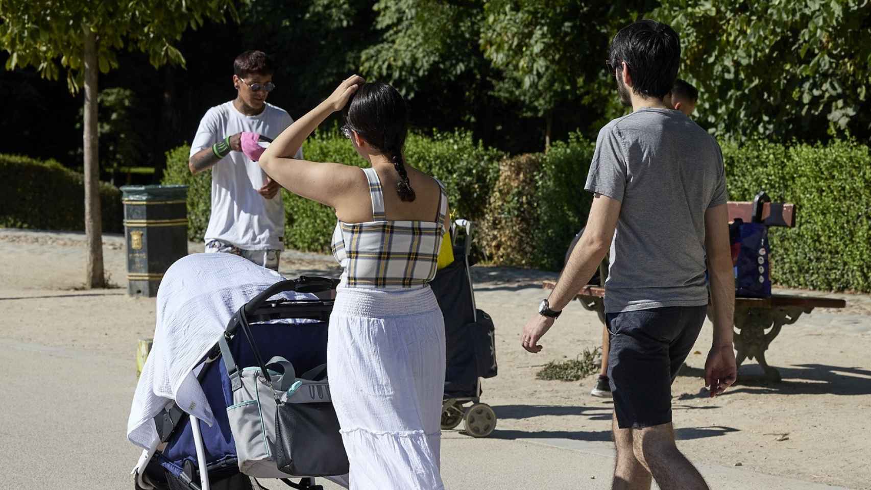 Varias personas pasean con un carrito de bebé en el parque de El Retiro.