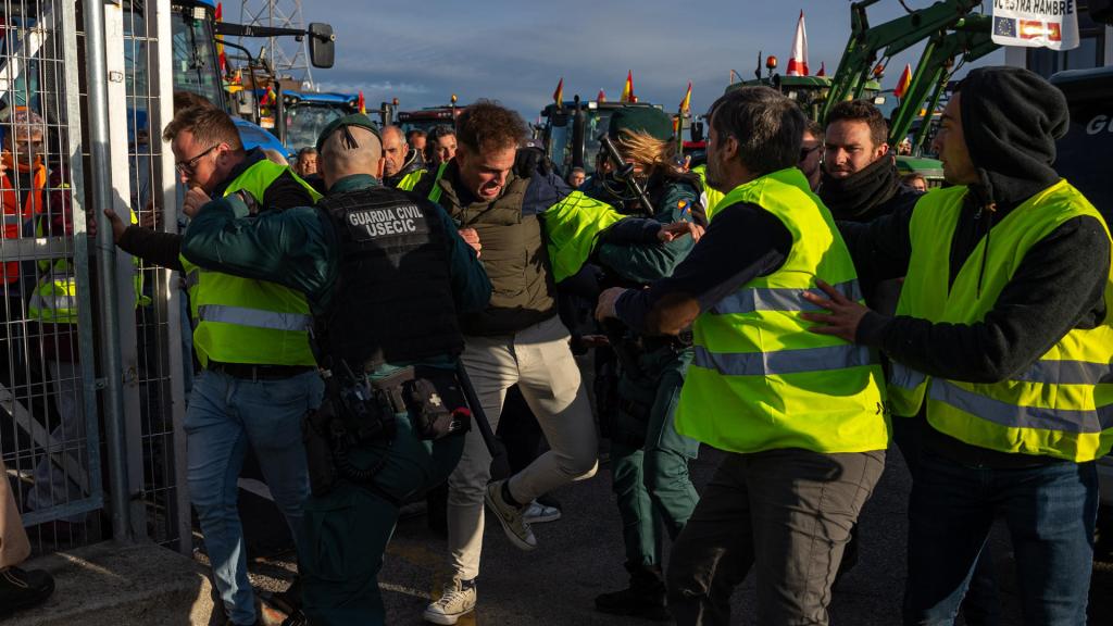 Agentes de la guardia Civil forcejean con los agricultores concentrados en la A-42 a la altura de Torrejón de la Calzada.