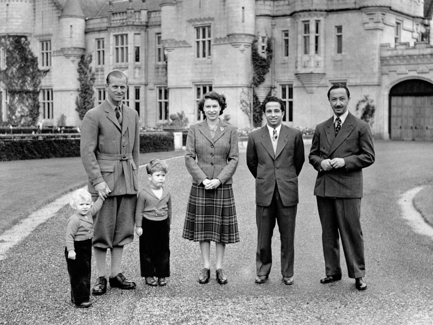 La reina Isabel II, vestida con una falda de tartán y una chaqueta de tweed, posa delante del Castillo de Balmoral, con sus invitados reales, el rey Faisal II y el regente de Irak, y el duque de Edimburgo, el príncipe Carlos y la princesa Ana, en 1952.