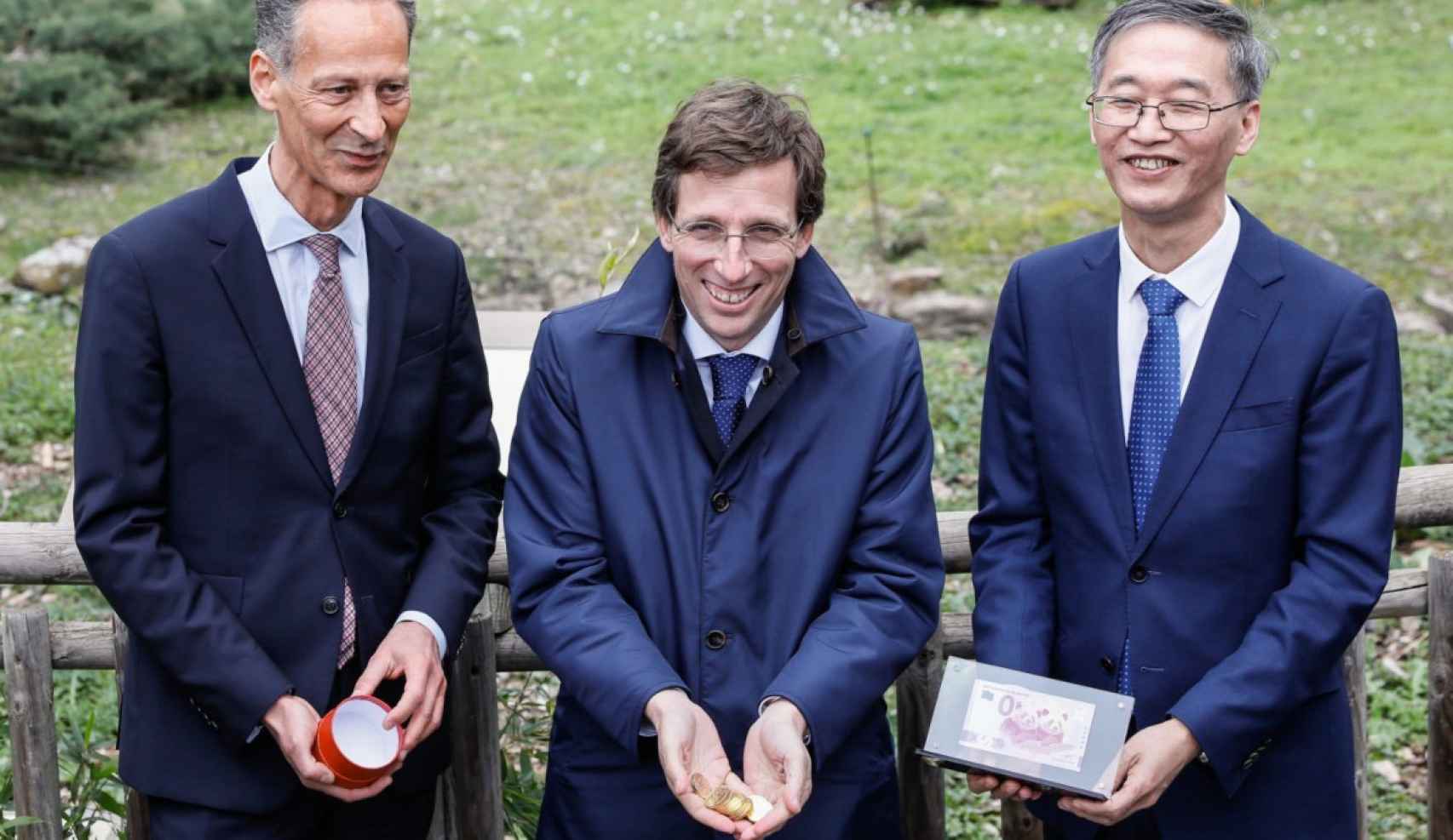 El alcalde, José Luis Martínez-Almeida, sujeta las monedas chinas acompañado por el embajador de la República de China, Yao Jing (derecha) y el consejero delegado del Grupo Parques Reunidos, Pascal Ferracci (izquierda).