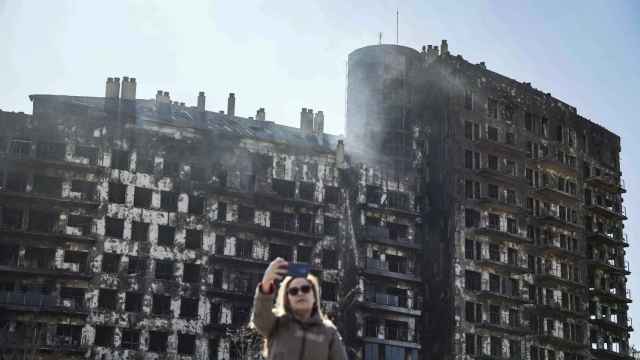 Una mujer se toma una fotografía ante el edificio incendiado. EFE/Biel Aliño