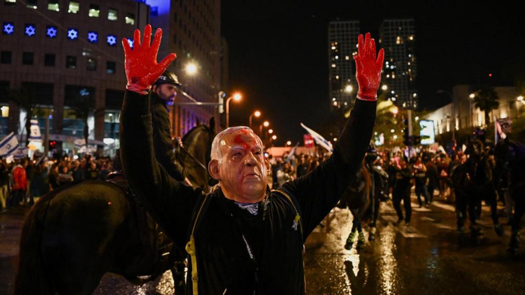Una persona muestra una máscara de Benjamin Netanyahu durante una protesta contra el gobierno israelí, en Tel Aviv.