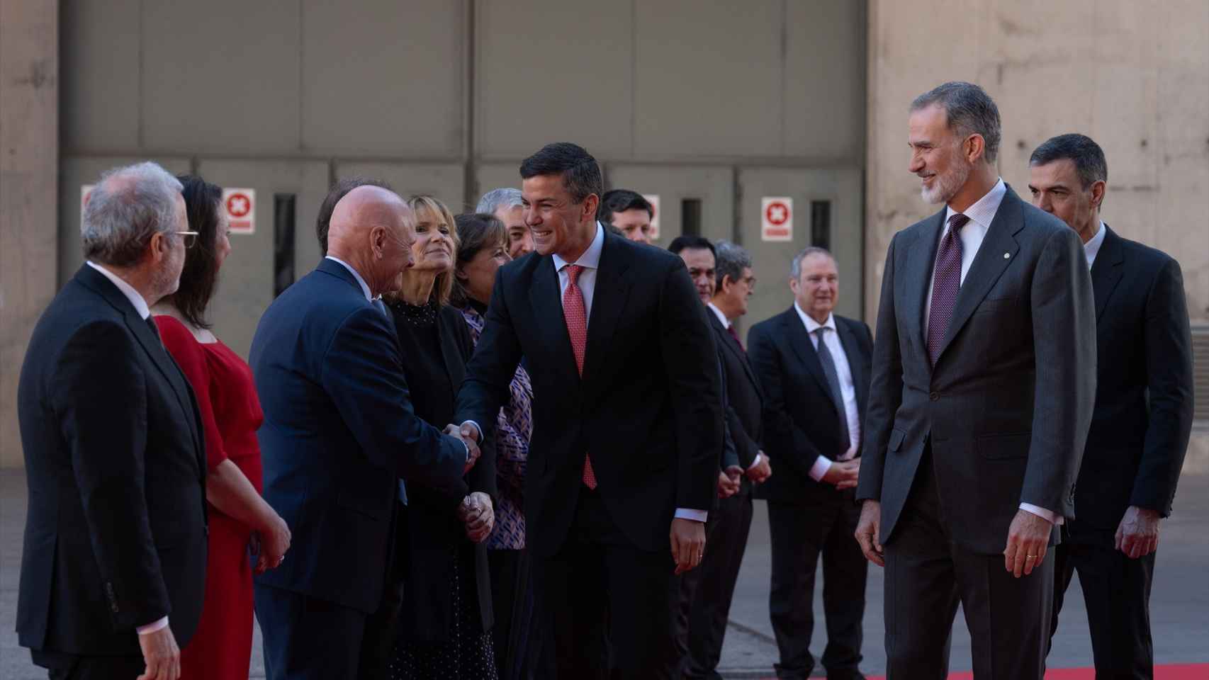 El presidente de Paraguay, Santiago Peña (c), saluda al director general de GSMA, John Hoffman (i) ante la presencia del rey Felipe VI.
