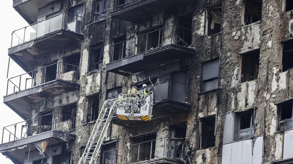 Bomberos en una grúa sanean la fachada quemada del edificio de Campanar. Rober Solsona / Europa Press