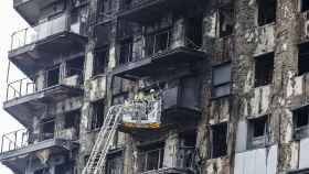Bomberos en una grúa sanean la fachada quemada del edificio de Campanar. Rober Solsona / Europa Press
