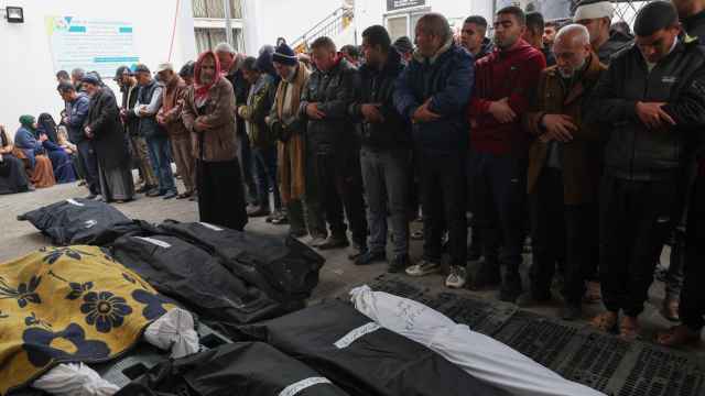 Decenas de palestinos frente a cadáveres de personas fallecidas en un ataque israelí en la Franja de Gaza.