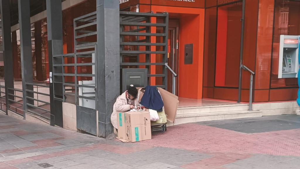 Una persona con sus enseres en la confluencia entre la Rambla y Alfonso El sabio de Alicante.