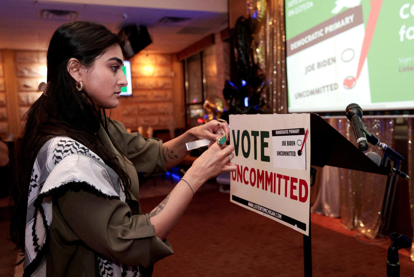 La activista Natalia Latif pega un cartel de Vote Uncommitted en una reunión en Dearborn (Michigan).
