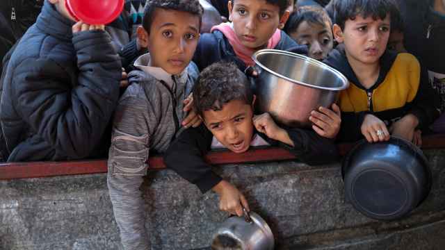 Varios niños esperan alimentos con ollas vacías en Rafah.