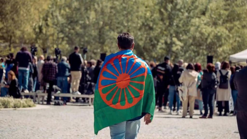 Un hombre caminando con la bandera gitana.