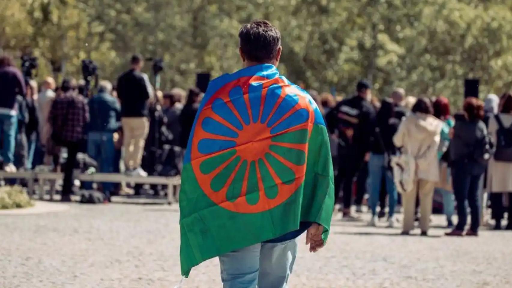 Un hombre caminando con la bandera gitana.