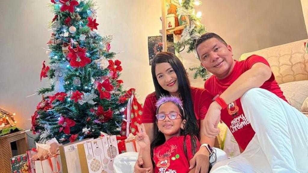La pequeña Sara en el árbol de Navidad, junto a sus padres, Melisa y Carlos.