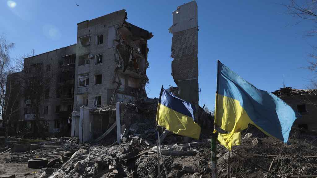 Dos banderas ucranianas ondean frente a edificios residenciales dañados en Orikhiv, en la región de Zaporiyia.