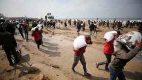 Los palestinos llevan bolsas de harina que agarraron de un camión de ayuda cerca de un puesto de control israelí en la ciudad de Gaza.
