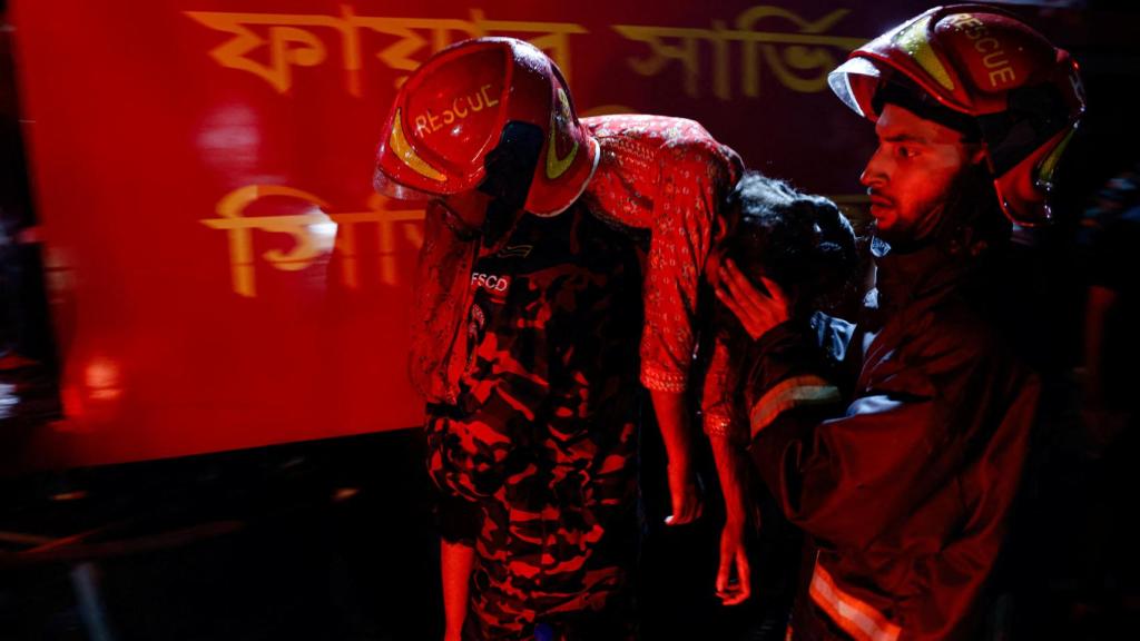 Los bomberos atienden a una víctima del incendio de Dhaka.
