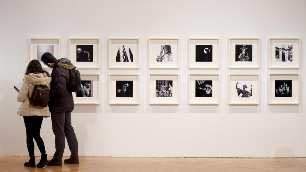 Dos personas observando las imágenes de Semana Santa expuestas