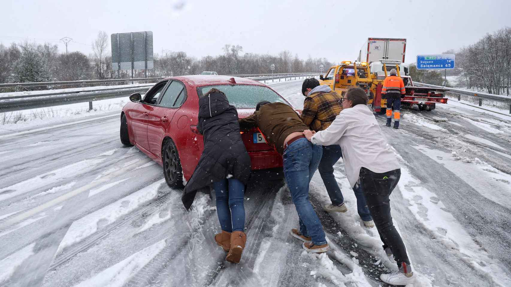 Varias personas empujan el coche tras quedarse atascado en una autovía por la nevada