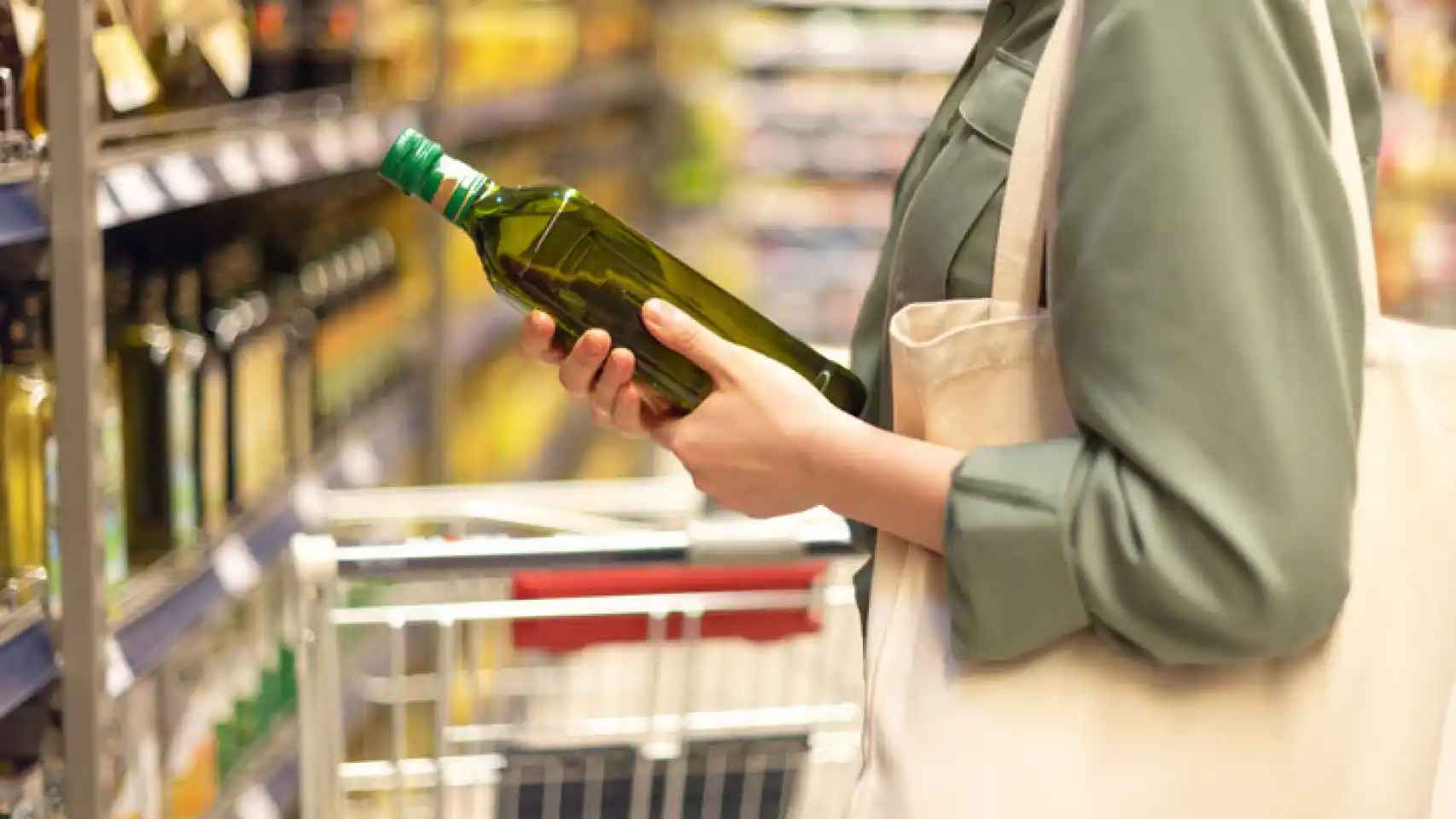 Imagen de una mujer con una botella de aceite en el supermercado.