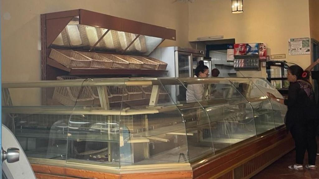 Una clienta compra en una panadería de La Habana con todos sus mostradores vacíos.