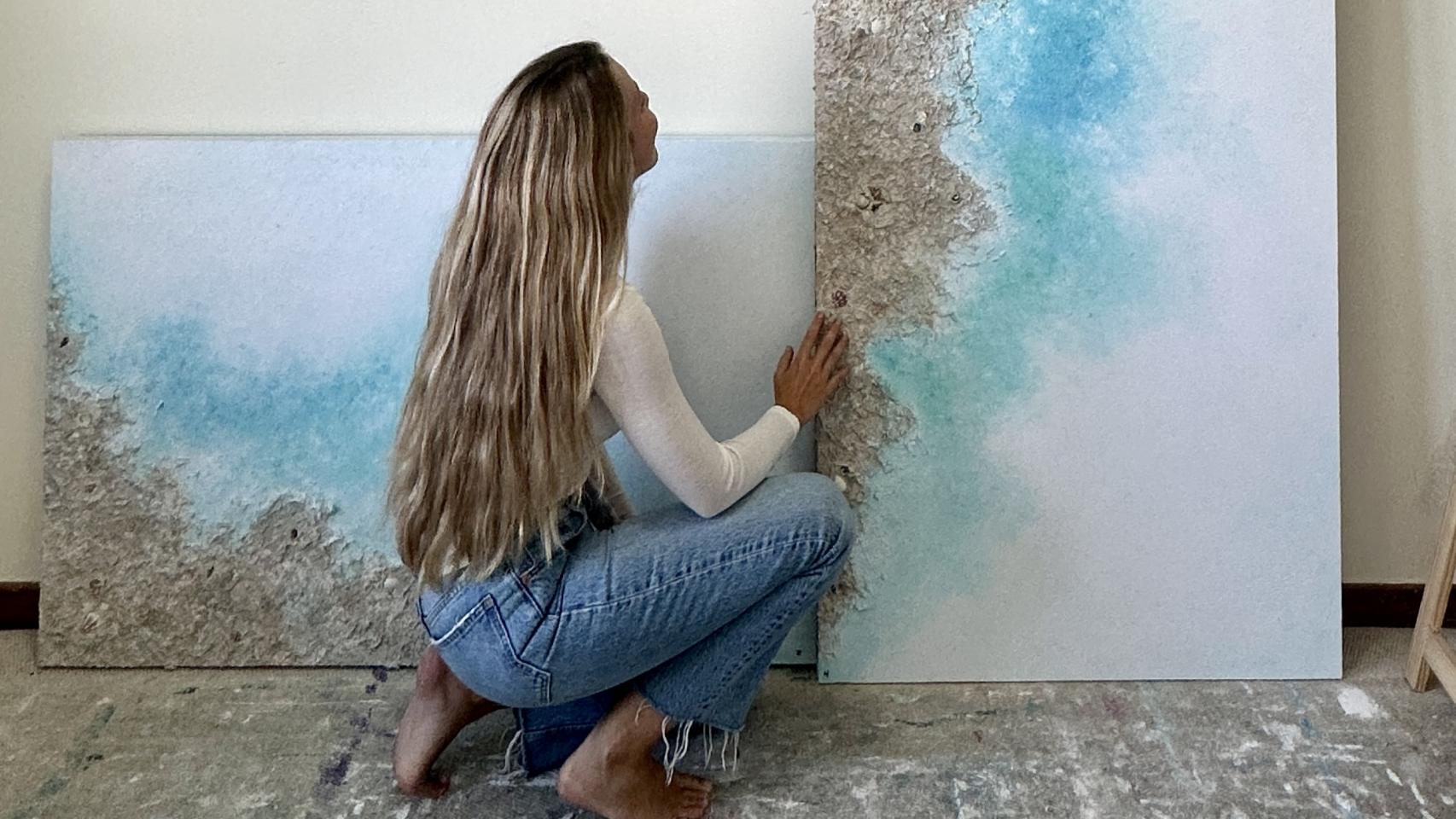 La pintora delante de sus producciones de arte.