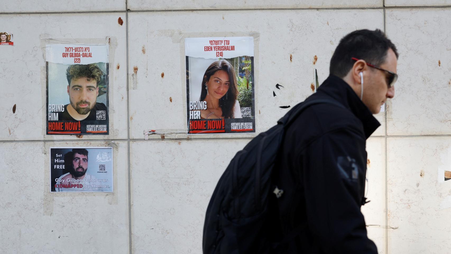 Un hombre pasa frente a carteles en Tel Aviv con imágenes de los secuestrados por Hamás el pasado 07 de octubre.