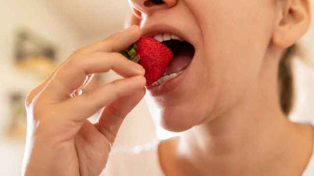 Una mujer se lleva una fresa a la boca