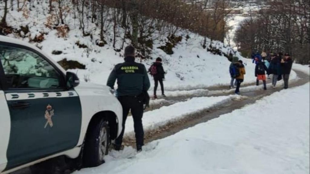 Los profesores caminando por la carretera con los niños para llegar al autobús
