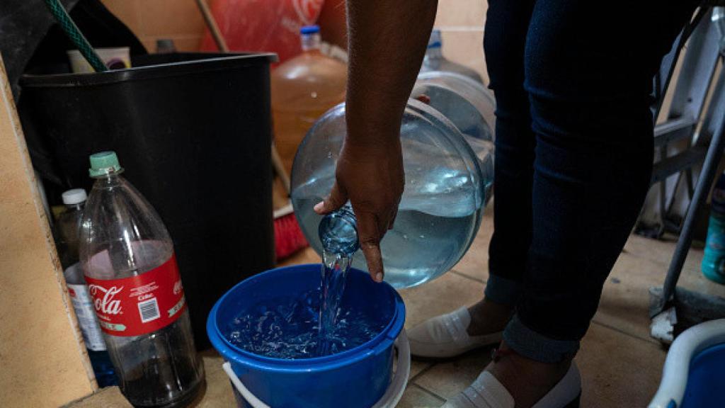 Una mujer vierte agua en un cubo en un apartamento en el barrio de Las Peñas en Iztapalapa.