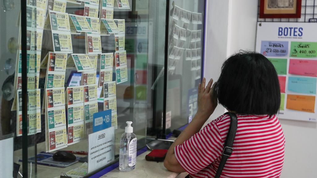 Una mujer compra lotería en una Administración de Lotería.