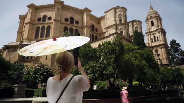Una turista fotografía la Catedral de Málaga protegiéndose del sol.